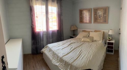 une chambre avec un lit blanc et une fenêtre dans l'établissement Joli appartement Quartier tranquille 13008 à 2 minutes du métro Perier, à Marseille