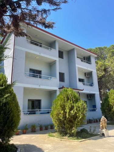 Un edificio blanco con árboles delante. en Canary Hotel, en Golem