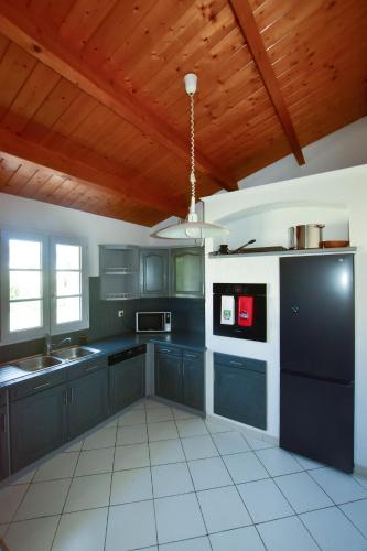 d'une cuisine avec des armoires noires et un plafond en bois. dans l'établissement Villa 12 pers - grand jardin - 8 min à pied de la plage - idéal pour détente ou remote-working, à Saint-Martin-de-Ré