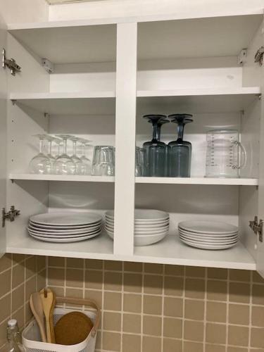un meuble de cuisine rempli d'assiettes et d'ustensiles. dans l'établissement Appartement Cosy avec fibre très bien équipé, à Briare