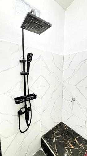 a shower in a bathroom with white marble walls at Kost Harian Semarang Murah in Semarang