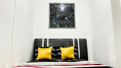a bed with yellow pillows and a picture on the wall at Kost Harian Semarang Murah in Semarang