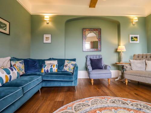 a living room with a blue couch and two chairs at Hammonds Farmhouse in Stroud