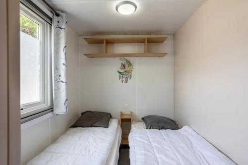 Mobil home proche du paradis des plages في سان جان دي مونت: سريرين في غرفة صغيرة بها نافذة