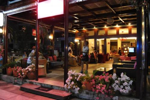 a woman standing in front of a restaurant with flowers at Okeania Seafront Rooms in Kamena Vourla in Kamena Vourla