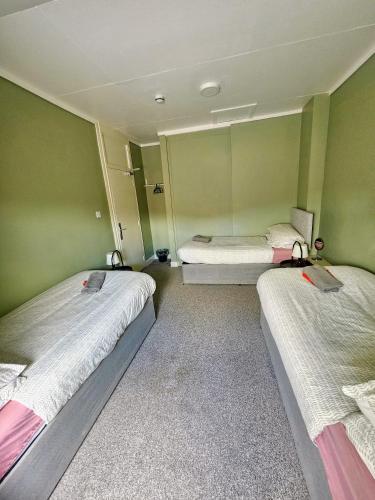 three beds in a room with green walls at Cunninghame House in Beith