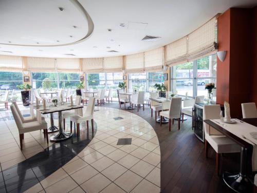 a dining room with tables and chairs and windows at Hotel Nadmorski in Gdynia