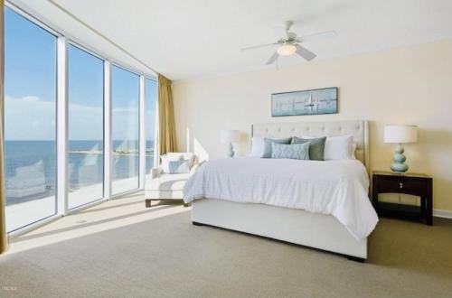 a bedroom with a white bed and large windows at Ocean Front Paradise in Biloxi