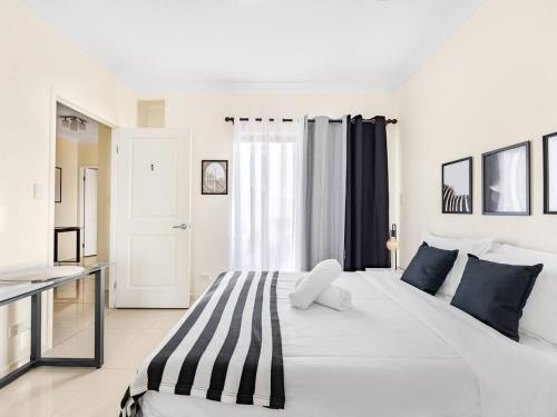 a white bedroom with a large white bed with blue pillows at Lovely Tiny Home at Sunnybank CBD On Street Parking in Brisbane