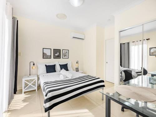 a white bedroom with a black and white striped bed at Lovely Tiny Home at Sunnybank CBD On Street Parking in Brisbane
