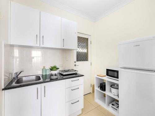 a white kitchen with white cabinets and a sink at Lovely Tiny Home at Sunnybank CBD On Street Parking in Brisbane
