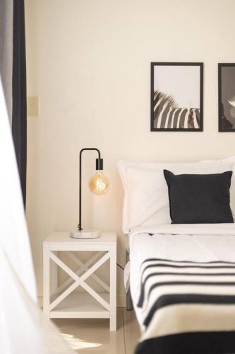 a white bedroom with a bed and a table with a lamp at Lovely Tiny Home at Sunnybank CBD On Street Parking in Brisbane