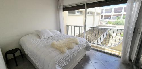 un ours en peluche blanc assis sur un lit avec un balcon dans l'établissement F1 Cosy 45m2, 2 mn mer, du port, cœur ville, à La Grande Motte