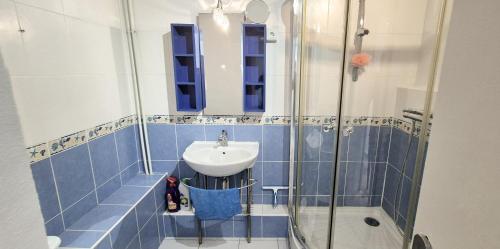 une salle de bain carrelée bleue avec un lavabo et une douche dans l'établissement F1 Cosy 45m2, 2 mn mer, du port, cœur ville, à La Grande Motte