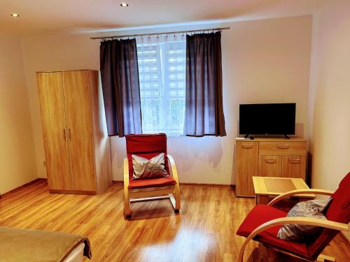 a living room with red chairs and a flat screen tv at Pod LIPÓWKAMI in Olsztyn