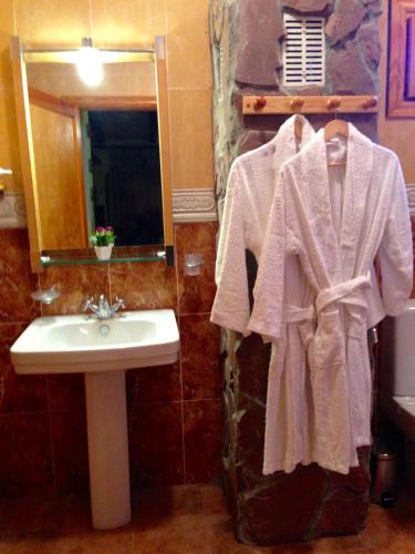 a bathroom with a sink and a white robe at Encanto de Aragón in Torres de Albarracín