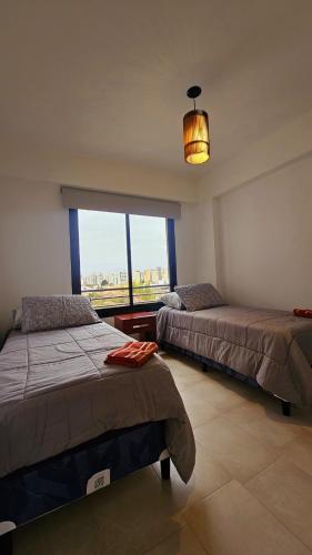 two beds in a room with a large window at Vi Hosting Anzoategui Aparts in Salta