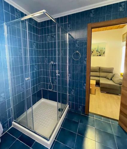 a blue tiled bathroom with a shower and a couch at Apartamentos Melgarden - La casa de Elechas in Elechas