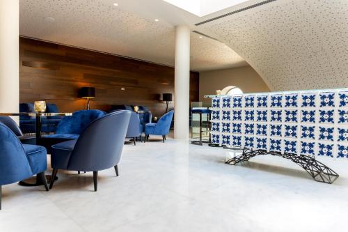 a waiting room with blue chairs and a table at 4615 Hotel in Felgueiras