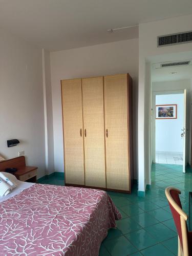 a bedroom with a bed and a cabinet in it at Hotel America in Marina di Camerota