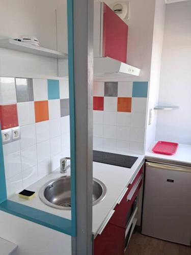 Elle comprend une petite cuisine avec un évier et du carrelage rouge et blanc. dans l'établissement Studio Arc En Ciel 1 - 25 allée des Pinons - 9-1, à Saint-Jean-de-Monts
