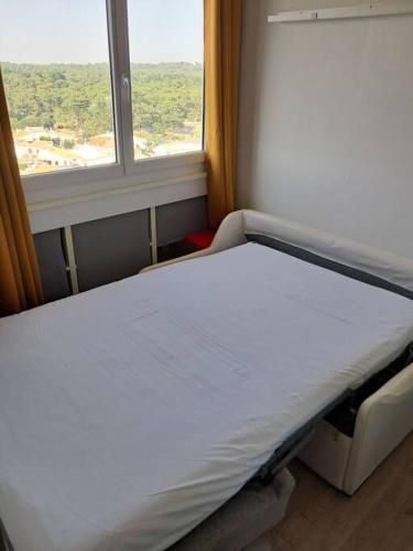 un lit dans une chambre avec une fenêtre dans l'établissement Studio Arc En Ciel 1 - 25 allée des Pinons - 9-1, à Saint-Jean-de-Monts