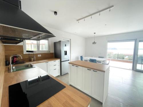 a large kitchen with white cabinets and a large window at Holiday house Mila in Rtina