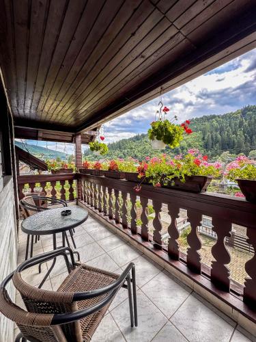 a balcony with a table and chairs and flowers at Perla Brazilor in Frumosu
