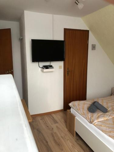 a bedroom with two beds and a flat screen tv at Zimmer Leuchtturm in Dagebüll