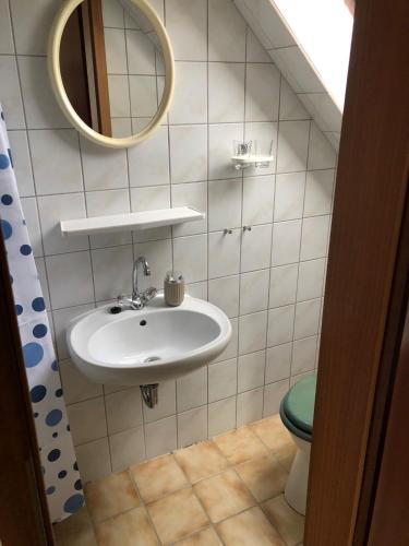 a bathroom with a sink and a toilet and a mirror at Zimmer Leuchtturm in Dagebüll