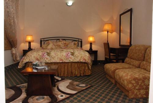a hotel room with a bed and a couch at Savoy Inn Guest House Islamabad in Islamabad