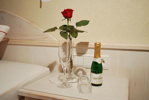 a rose in a vase and a bottle of champagne at Landhaus Notburga in Gries im Sellrain