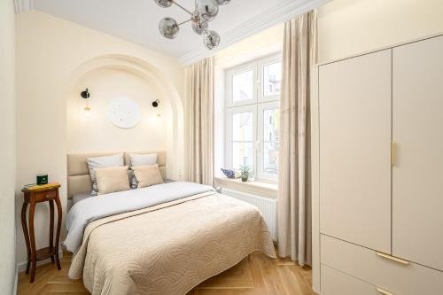 a white bedroom with a bed and a window at Quiet Apartment on the Main Square, 2 Bathrooms in Wrocław