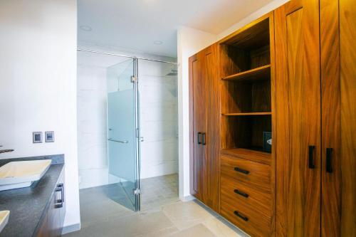 baño con ducha y armario de madera. en Pool, BBQ & Ocean View | Modern Amapas Condo, en Puerto Vallarta
