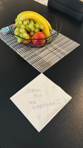 a plate of fruit on a table with a note at MF Apartment in Nea Kalikratia