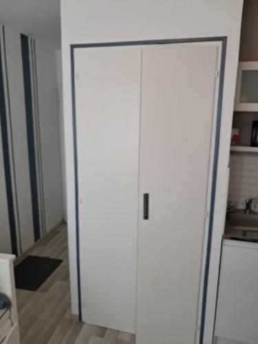 - une porte blanche dans une chambre avec cuisine dans l'établissement Studio Arc En Ciel 2 - 27 allée des pinons - 6-1, à Saint-Jean-de-Monts