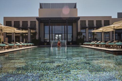 a woman standing in the water in a swimming pool at Conrad Rabat Arzana in Rabat