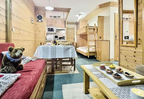 une pièce avec une table et un ours assis sur un canapé dans l'établissement Résidence Le Pramecou - 2 Pièces pour 6 Personnes 16, à Tignes