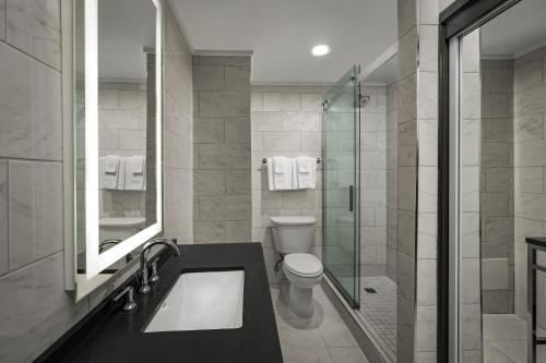 a bathroom with a toilet and a glass shower at The Admiral, Downtown Historic District in Mobile
