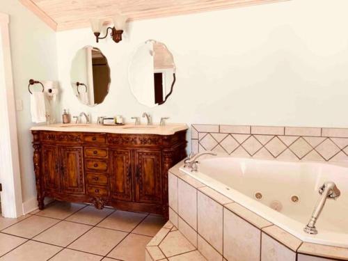 bagno con vasca, lavandino e specchio di Emigrant's Inn a Fredericksburg