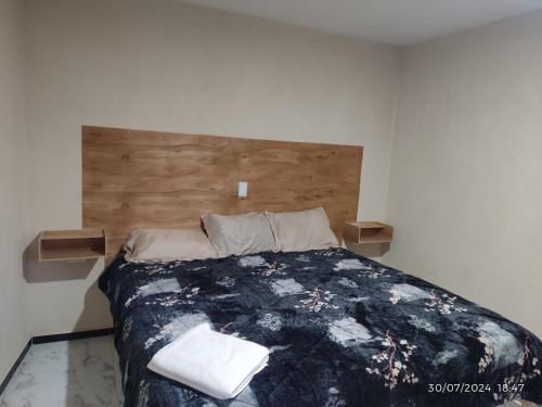 a bedroom with a large bed with a wooden headboard at Hotel Mextlitlán Tierra de Lunas in Zacatlán