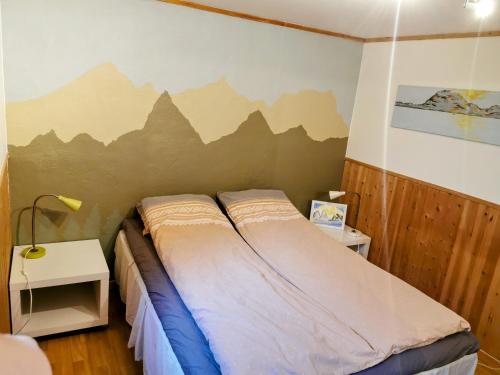 a bedroom with a bed with a mountain mural on the wall at Loghouse apartment in arctic wonderland! in Kvaløya