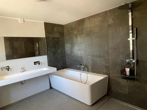 ein Badezimmer mit einer weißen Badewanne und einem Waschbecken in der Unterkunft Quinta do Coelhoazul in Quelfes