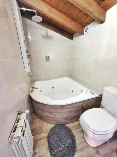 a bathroom with a white tub and a toilet at Las Victorias Suites Bariloche in San Carlos de Bariloche