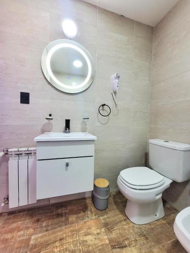 a bathroom with a toilet and a sink and a mirror at Las Victorias Suites Bariloche in San Carlos de Bariloche