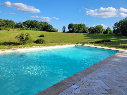 - une piscine d'eau bleue dans un champ dans l'établissement La Ferme du Peytavit - Stunning 3 Bed-Stone Barn, à Couze-et-Saint-Front