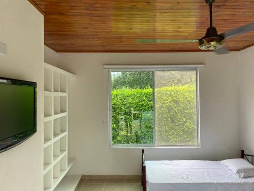 a room with a window and a bed and a television at Acogedora casa de descanso con piscina privada in Melgar