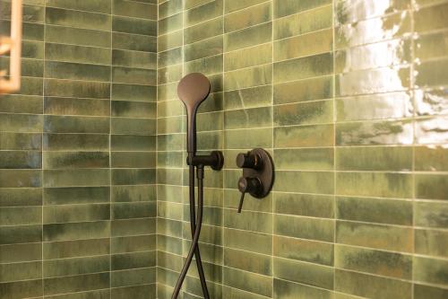 a shower head in a bathroom with green tiles at Casa Rina in Ostuni