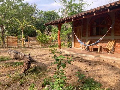 a house with a hammock in front of it at La casa de ladrillo, Las Planadas near Yankee Beach in Escamequita
