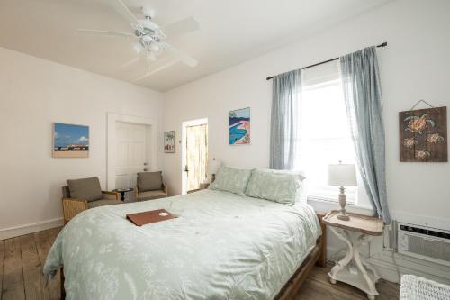 a white bedroom with a bed and a window at The Speakeasy Inn and Rum Bar in Key West